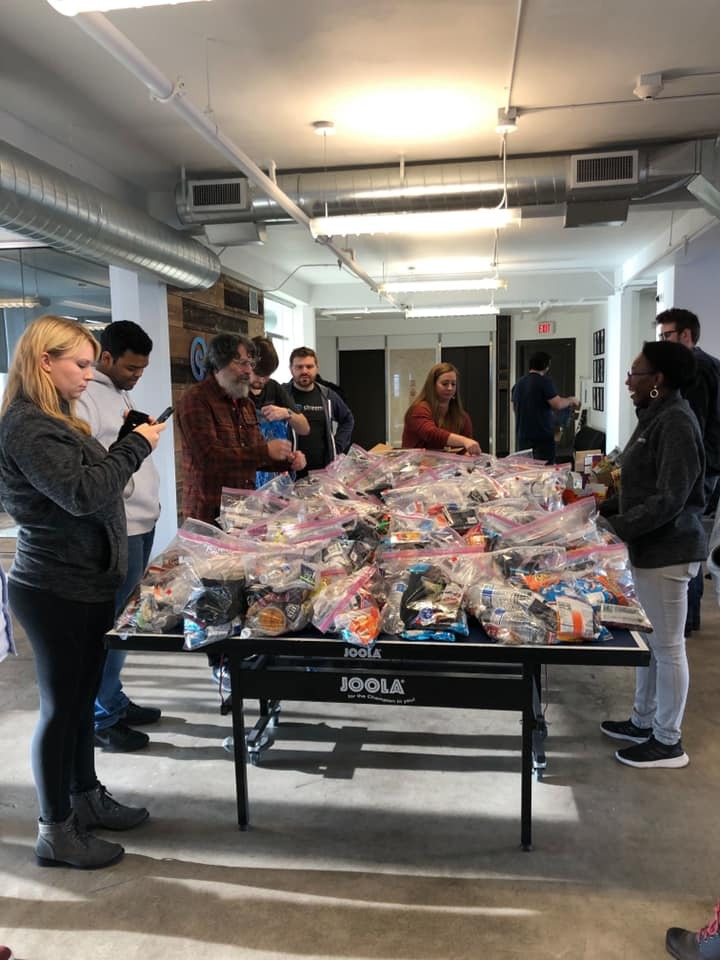 Employees stand around a ping pong table packing candy